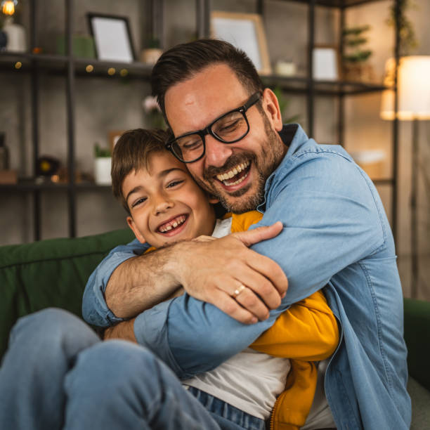 il papà abbraccia il figlio e condivide l'amore con lui, trascorre del tempo insieme a casa - festa del papà foto e immagini stock