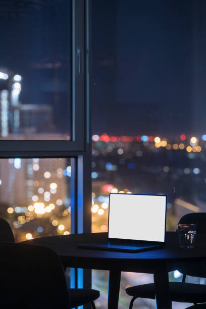 Open laptop with blank screen on wooden table in hotel with panoramic window