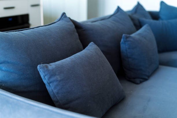 Selective focus on blue cushion on modern sofa in living room. Velour fabric on couch. Concept of replacement upholstery at soft modular furniture
