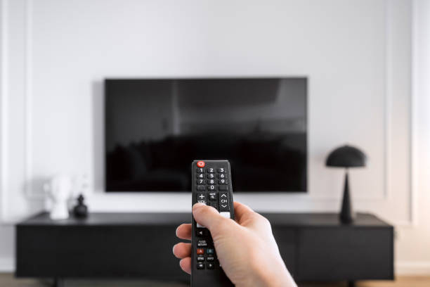 istock Woman hand hold remote control, press button and turn on television 2152242388