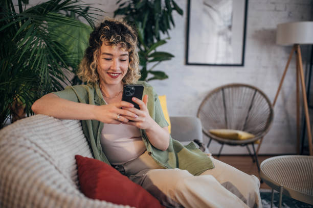 istock Young woman enjoying smartphone at cozy home 2152242436