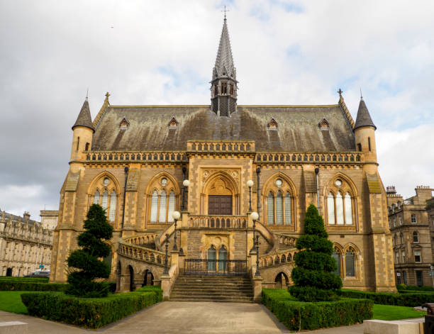 Glasgow, Scotland - July 13 2025: Visitors relaxing on the green lawn of Kelvingrove Park in front of the grand Kelvingrove Art Gallery and Museum under a cloudy sky