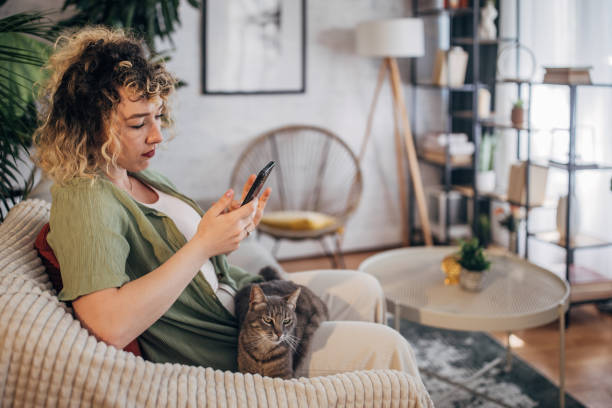 istock Woman relaxing with phone and cat on sofa 2152243630