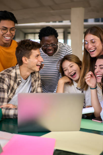 istock Group of young diverse students people laughing using laptop in the cafeteria on university campus 2152244736