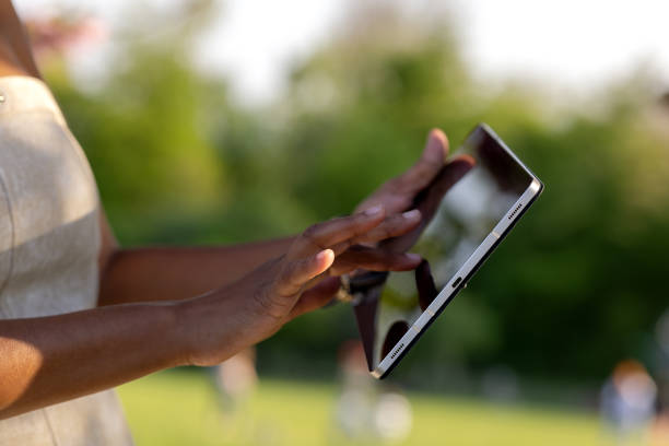 A middle-aged Brazilian woman uses a tablet in her daily life while on a walk in the park in the afternoon.