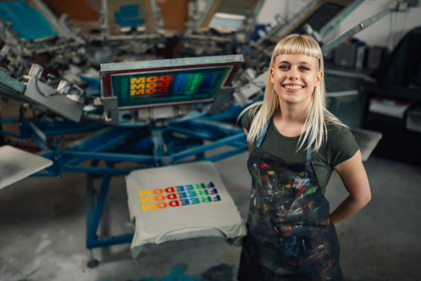 istock Happy print shop worker standing near screen printing press and smiling 2152254597