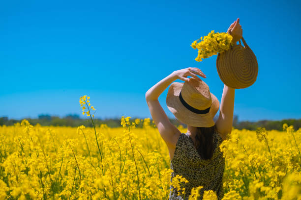 istock Woman raises hands, holding round woven bag from sturdy thread, ideal for budding businesses, with blooming rapeseed field in background. 2152254809