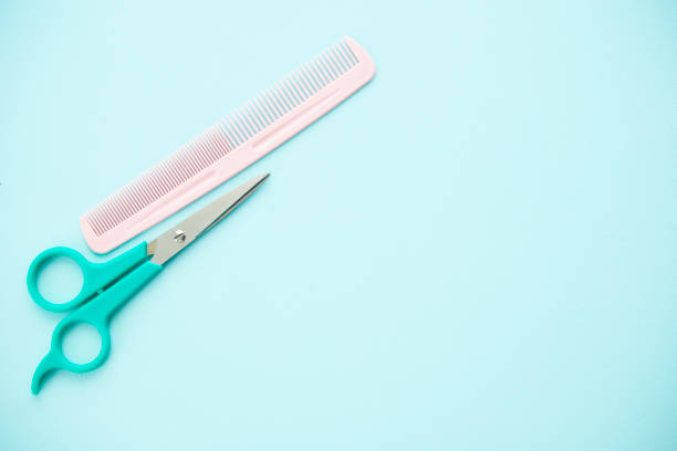istock A pair of haircutting scissors and a comb on a blue background with space for text 2152257097