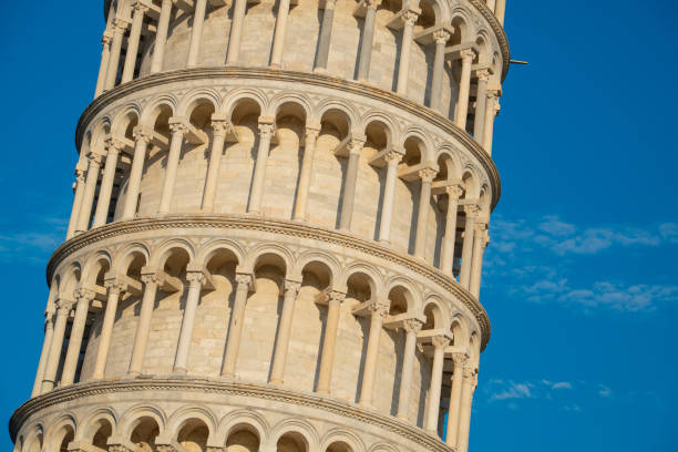 Detailed close-up of the Leaning Tower of Pisa displaying the intricate work and tiered design against a clear blue sky in Italy, pisa