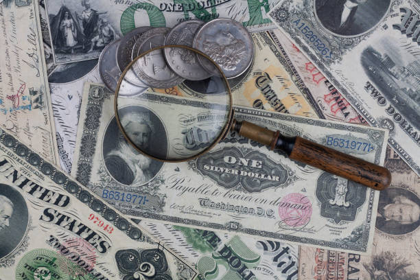 istock Old US banknotes and silver certificates with silver dollar coins and magnifying glass 2152261197