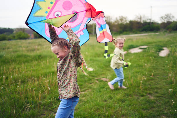 two little sisters and mother run and launch a kite in the field