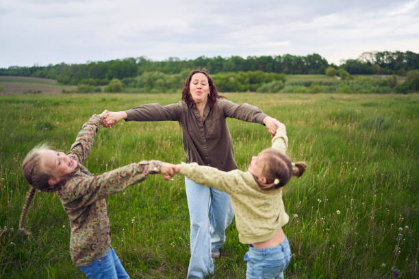 mother and two sisters circle in the field holding hands
