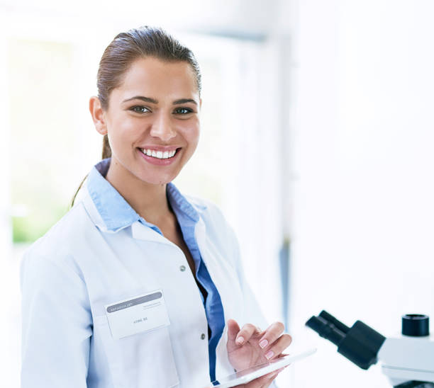 istock Scientist, portrait and smile with laboratory, microscope and tablet for research and discovery. Woman, science and lab coat for forensics, breakthrough and drug innovation and life extension 2152262048