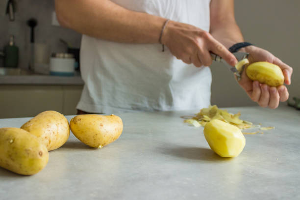 istock a man peeling potatoes on a grey kitchen counter with a potato peeler 2152263551