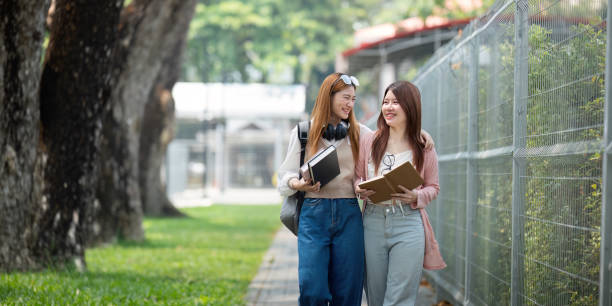 University student girl friends with learning book college while walking in campus