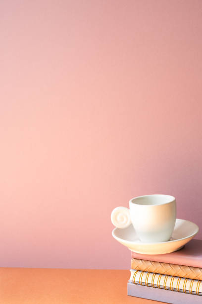 istock Stack of notebook and coffee cup on orange table. pink wall background with copy space 2152277248
