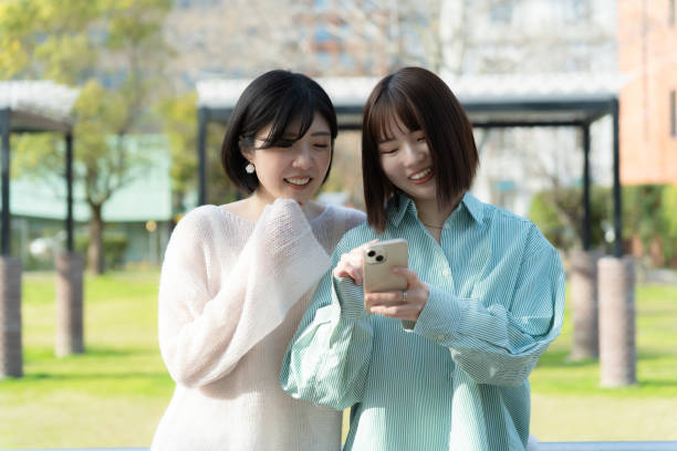 istock Women talking happily while looking at their phones 2152277467