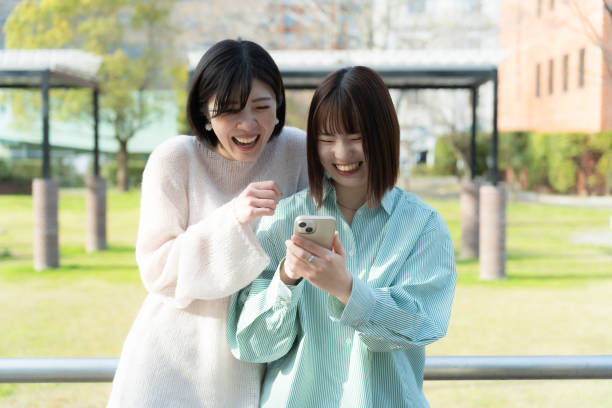 istock Women talking happily while looking at their phones 2152277496