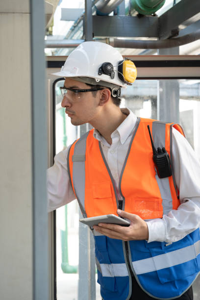 istock Portrait Asia male engineer in protective workwear is checking a electrical control cabinet or circuit electric control button with walkie talkie at rooftop building 2152278283