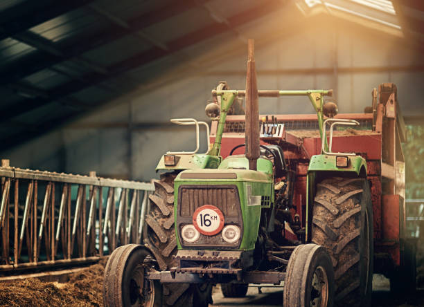 Farm, machine and old tractor in barn with dirt, rust and dust in storage warehouse on land. Vintage, retro and plow truck in abandoned factory shed or tools for farming production or agriculture