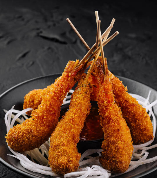 istock Crispy breaded shrimp skewers on dark plate 2152283480