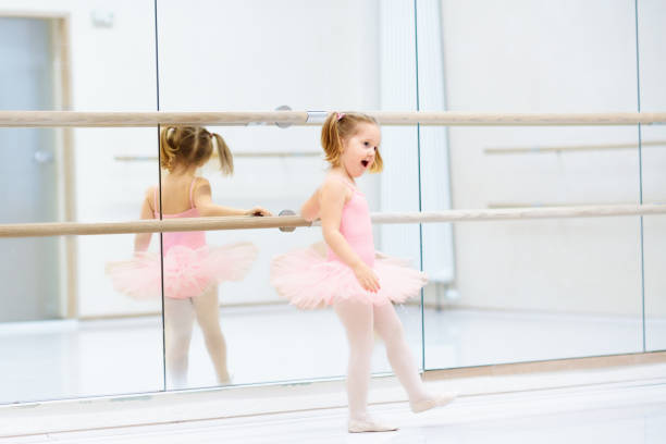 Little ballerina girl in a pink tutu. Adorable child dancing classical ballet in a white studio. Children dance. Kids performing. Young gifted dancer in a class. Preschool kid taking art lessons.