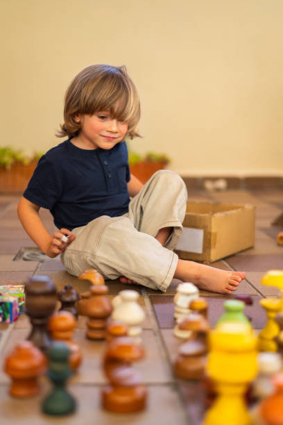 Adorable 4 Year Old Blonde Boy Playing With Colorful Wooden Pieces In The Yard Of His House.