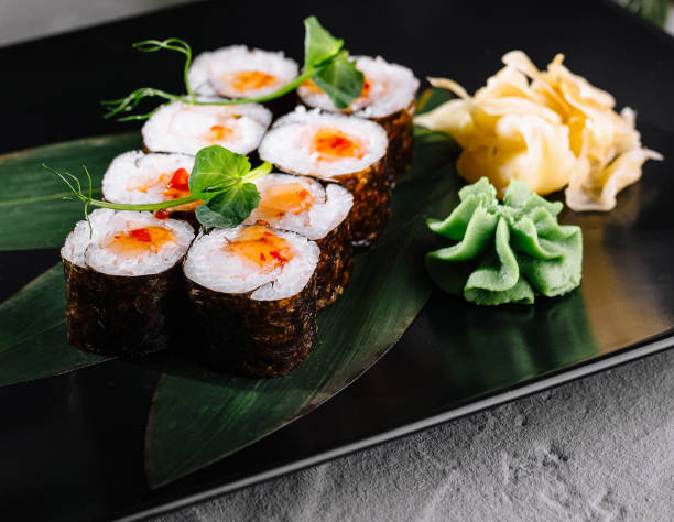 istock Sushi array garnished with wasabi and ginger on a stylish black plate, adorned with greenery 2152284845
