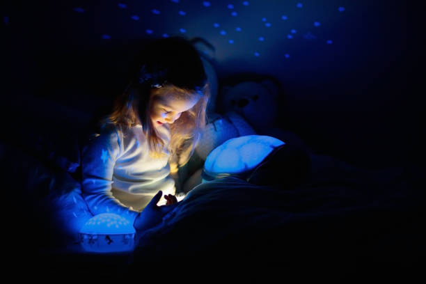 istock Little girl reading a book in bed 2152285526