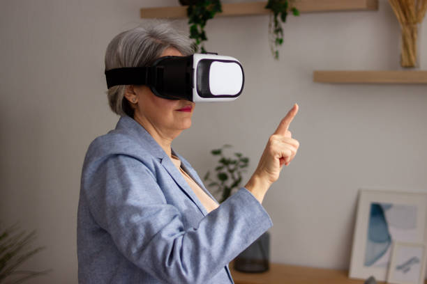istock Senior woman using virtual reality headset at home 2152294238