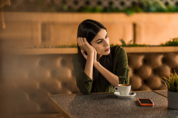 Lonely young woman sitting alone at a restaurant and thinking.