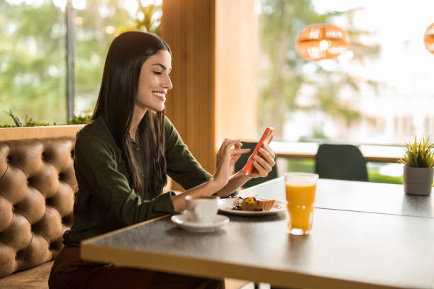 istock Happy woman using phone while having dessert at a restaurant. 2152294673