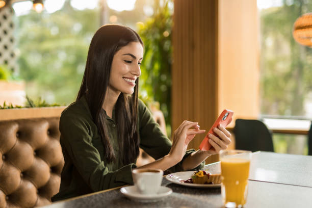istock Happy woman using phone while having dessert at a restaurant. 2152294741