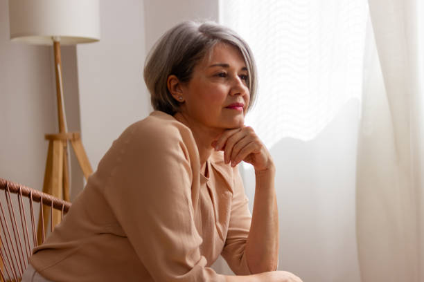 istock Contemplative senior woman looking out window 2152295248