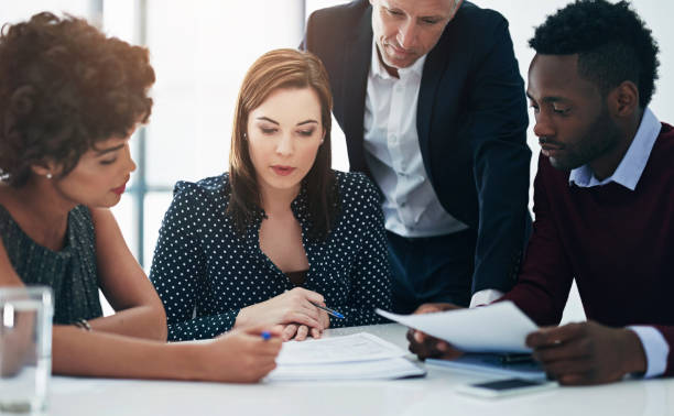 istock Lawyer, group and paperwork at meeting with people, reading and thinking for problem solving at legal agency. Team, men and women by documents, review and talk for investigation at corporate law firm 2152295311