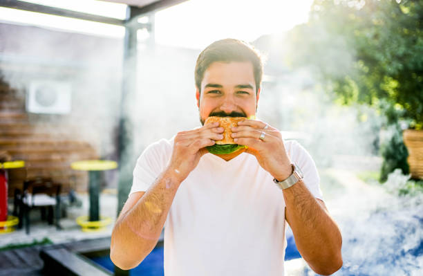 istock Man eating a hamburger at a barbecue party 2152295724