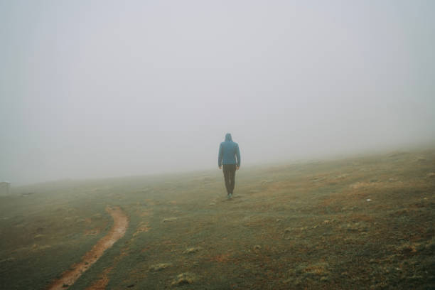 istock Man walking away on misty road. 2152296322