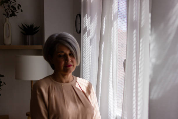 istock Serene mature woman by window light 2152296567