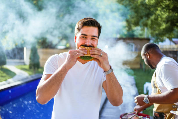 istock Man eating a hamburger at a barbecue party 2152296964