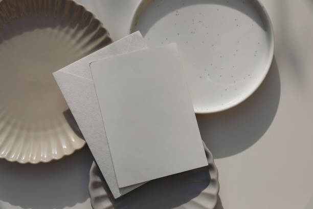 istock Blank greeting card, invitation mockup, envelope in sunlight. Different plates on beige table background. Soft shadows. Neutral still life, web banner. Food, restaurant, craft concept. Flat lay, top. 2152301527