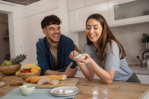Happy woman making a sandwich during breakfast with her boyfriend.