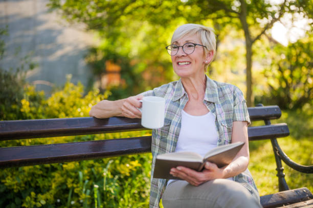 Senior woman reading book and drinking coffee