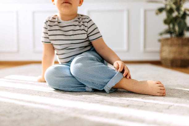 istock Cute barefoot casually clothed boy sitting on a floor at home 2152306167