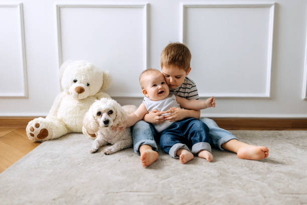 istock Cute little boys sitting on a floor with their cute white dog 2152306552