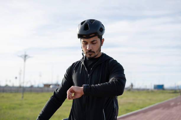 istock Brunette man on bicycle using smartwatch in park 2152306753