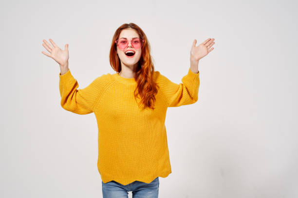 istock cheerful woman in pink glasses gesturing with her hands yellow sweater studio 2152306874