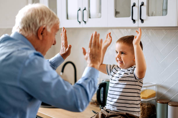 Cute little boy having fun with his grandfather in a domestic kitchen