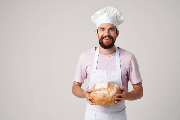 istock bearded man in a white apron with bread in his hands baking light background 2152312908