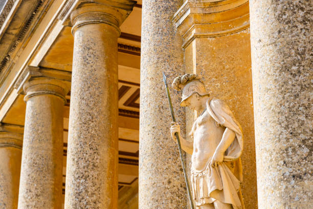 A close-up of a marble statue depicting Bacchus, the Roman god of wine, raising a bunch of grapes in his right hand. The sculpture is located in Piazza del Popolo, Rome, Italy. No people.