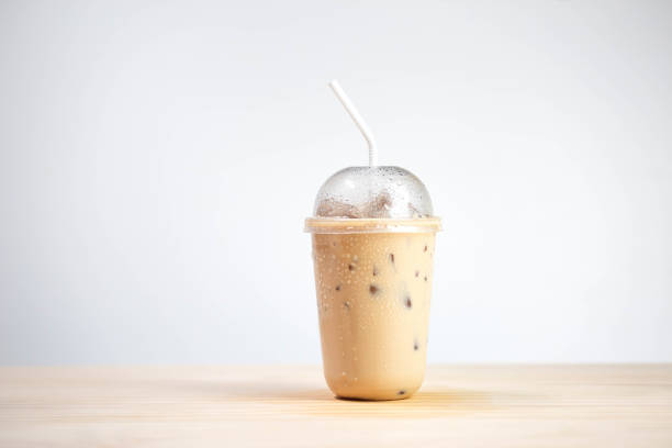 Iced coffee mocha or coffee latte in takeaway cup on wooden table. coffee package for takeaway, Cold beverage product.